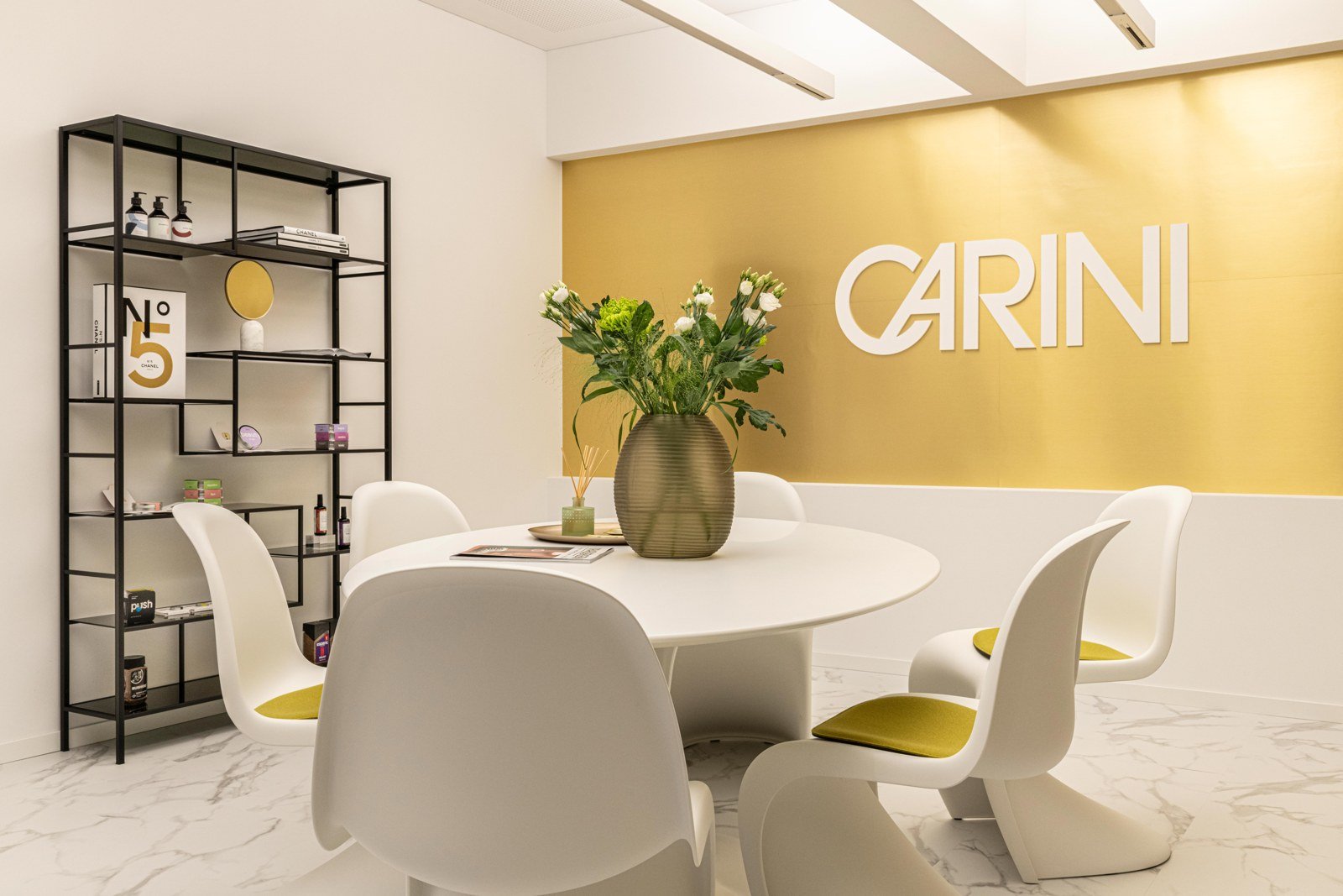 Heller Raum mit weißen Möbeln und goldener CARINI-Wand