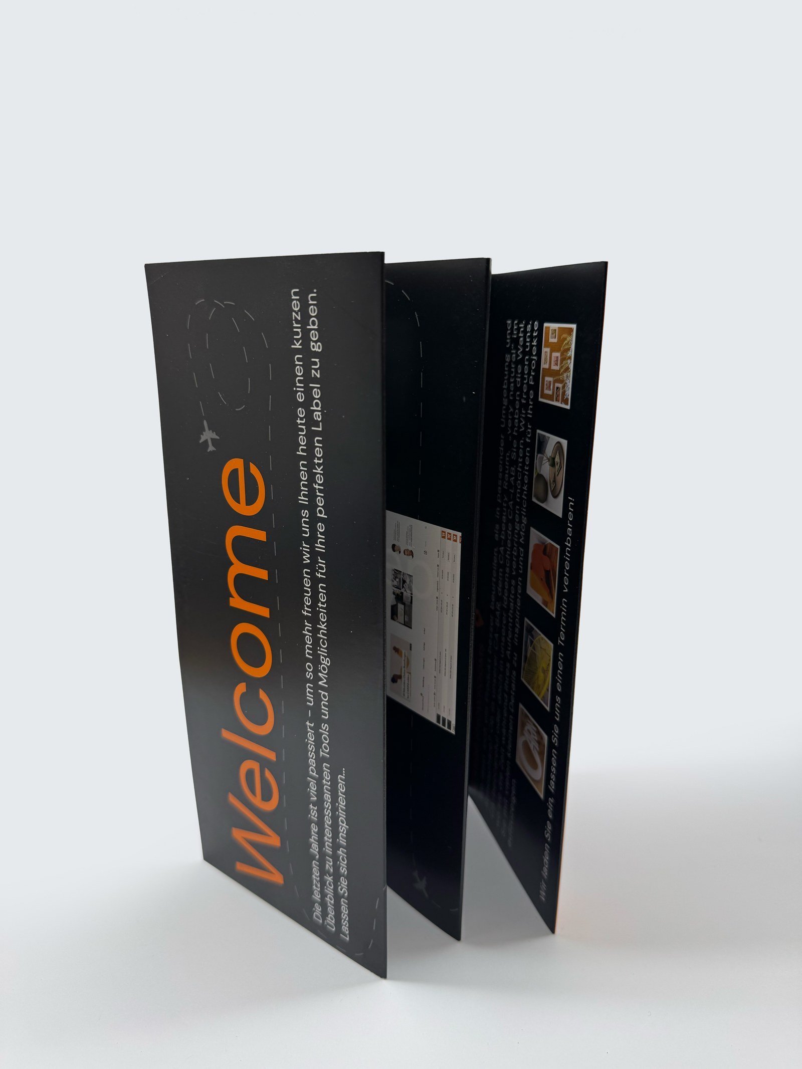 Aufgefalteter schwarzer Welcome-Flyer mit orangefarbener Typografie